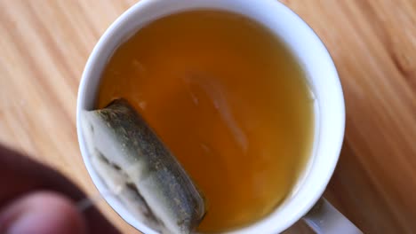 cup of tea with tea bag on wooden table close-up