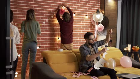 hombres y mujeres divirtiéndose preparando una fiesta para un amigo, colgando guirnaldas