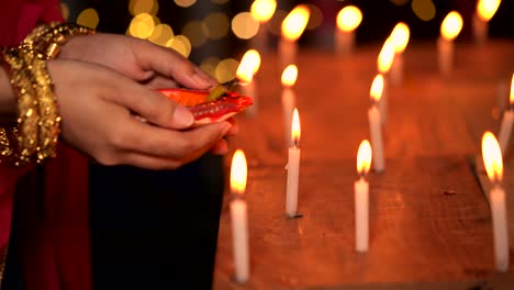 mujer hindú iluminando una lámpara diya
