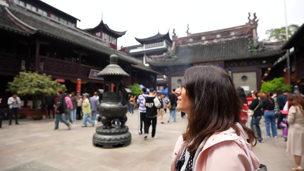 Tourist woman admiring the City God Temple courtyard and incense burner, also known as Chenghuangmiao. Shanghai, China