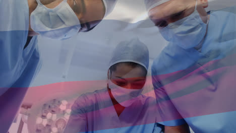 animation of waving russia flag against team of diverse surgeons performing operation at hospital