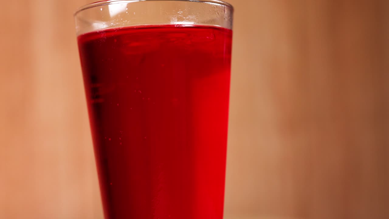 Un vaso lleno de refresco rojo