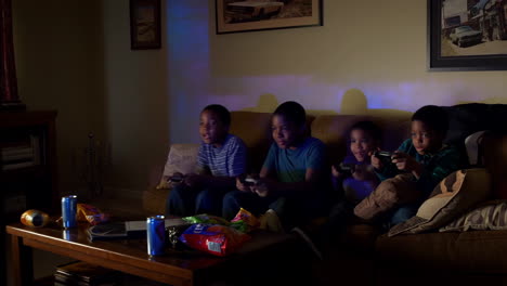 four boys playing video games on a couch