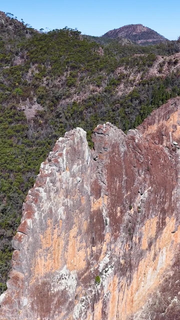 Un lento zoom indietro rivela la frastagliata formazione rocciosa Breadknife all'interno del Parco Nazionale Warrumbungle, Australia.