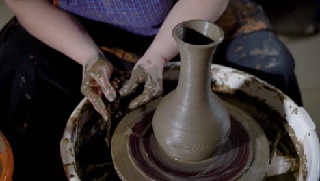 close up shot of a woman's hands, the mother creates a pattern on a clay pot with tools, the product stands on a potter's wheel