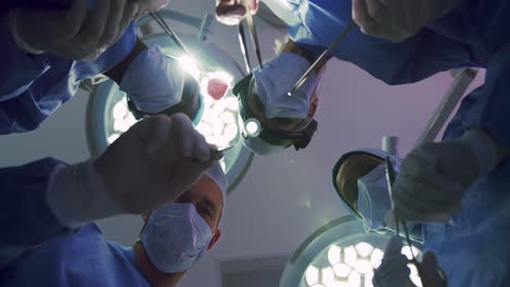vista hacia arriba de cirujanos multiétnicos que realizan cirugías en la sala de operaciones del hospital