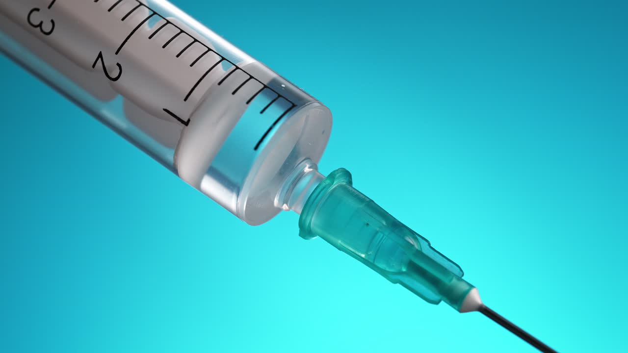 dar inyección o vacuna con una jeringa médica desechable con aguja en macro sobre un fondo azul claro