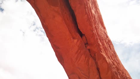 Tracking-shot-along-the-span-of-a-huge-sandstone-arch-with-lens-flare-in-Arches-National-Park,-Utah