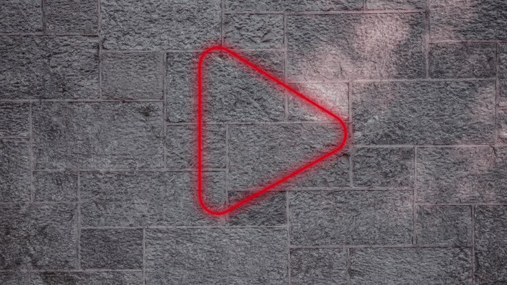 Animation of glowing neon play icon on brick wall