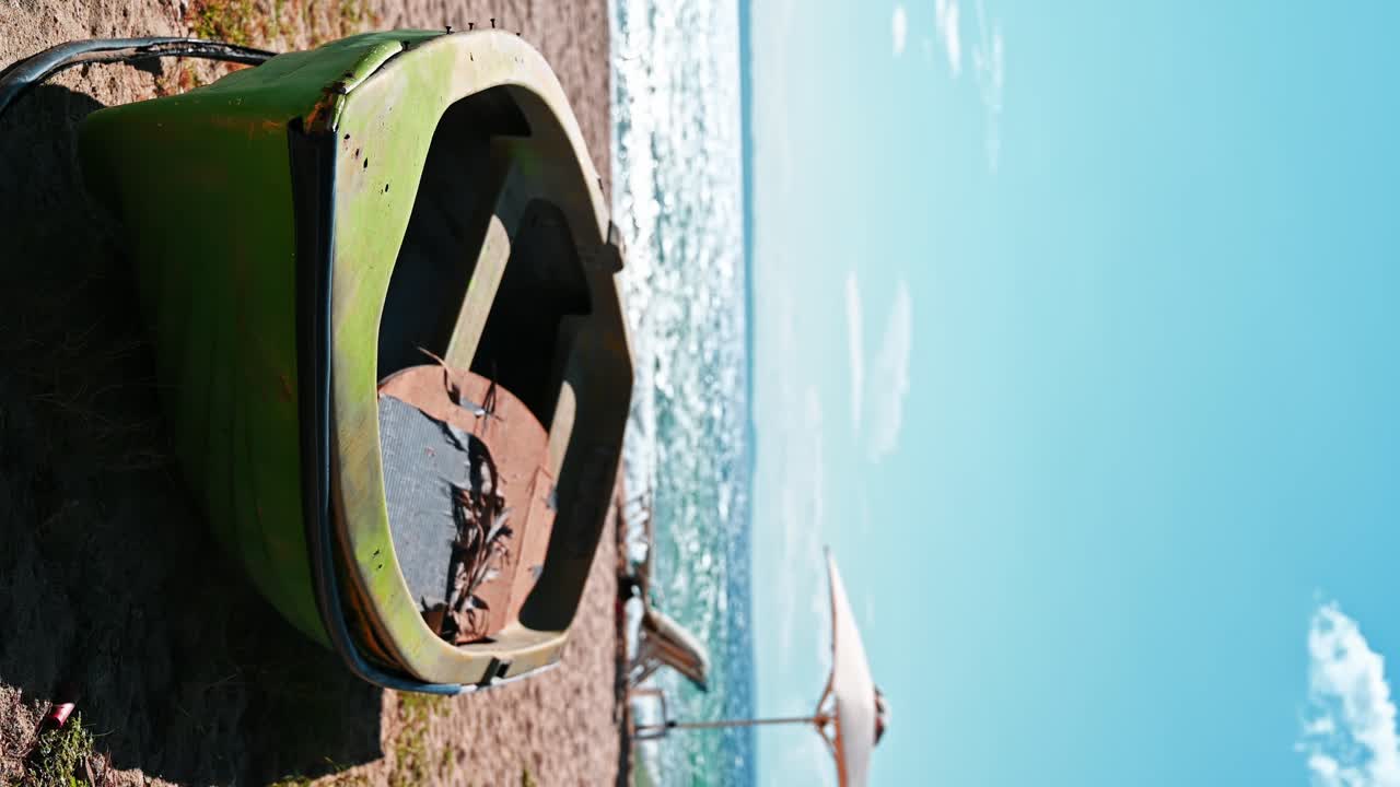 Beached boat made of green colored metal, umbrellas, sunbeds and Aegean sea on the background in Nikiti, Greece. Vertical shooting