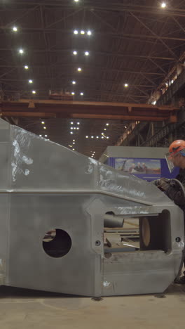 industrial worker engaged in metalwork on a large structure within a factory