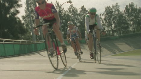 a group of cyclists ride around a track 1