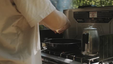 Person-Breaking-Egg-Over-Frying-Pan-Outdoor-In-nature