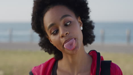 portrait-cute-young-african-american-woman-making-faces-enjoying-crazy-fun-on-summer-vacation-day-seaside-background-wearing-sporty-fashion