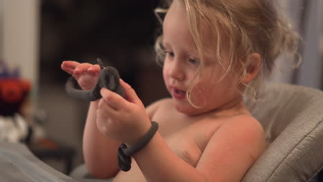 funny little girl trying to make playdough bracelets