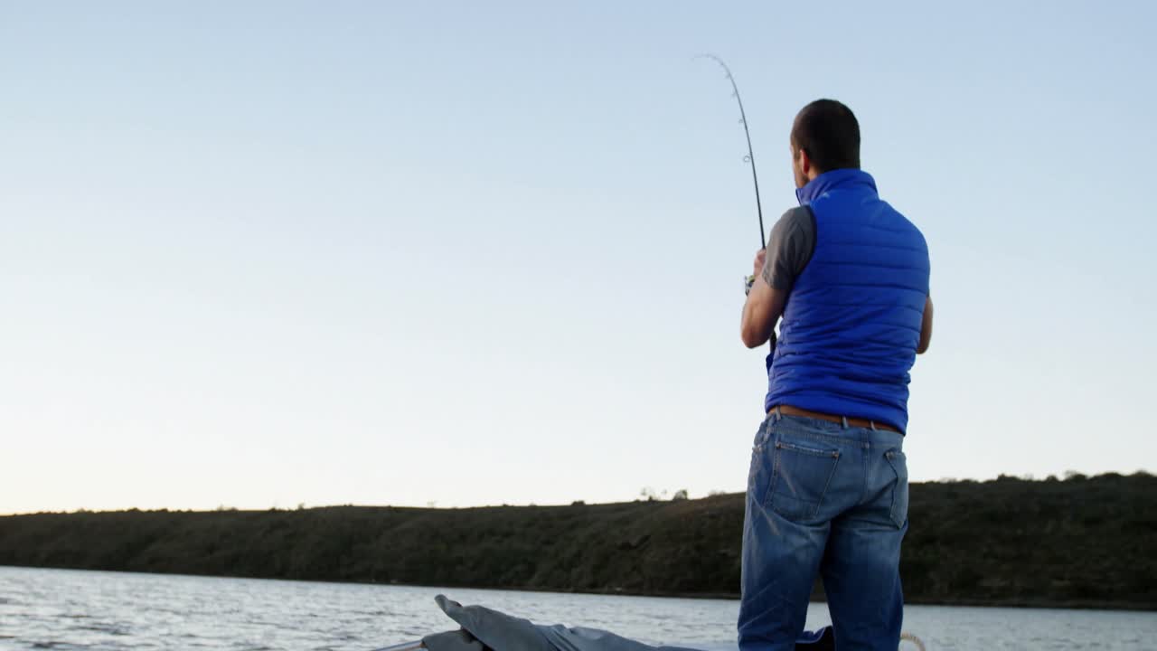 Pria memancing sambil berdiri di perahu motor 4K
