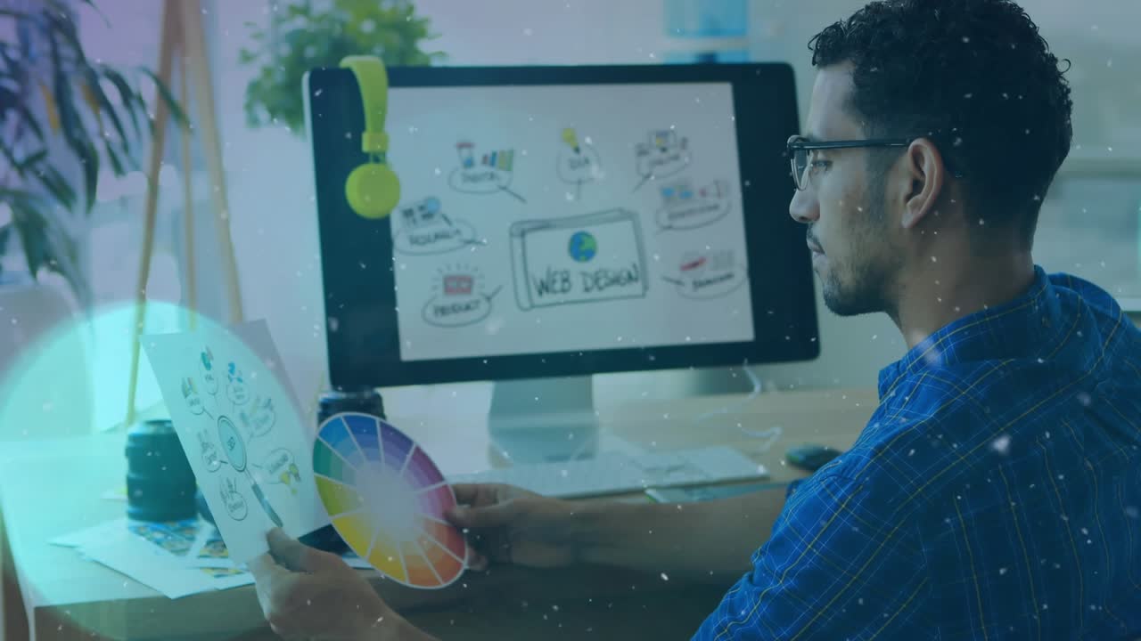 Animation of white particles over male graphic designer holding a document and color swatch