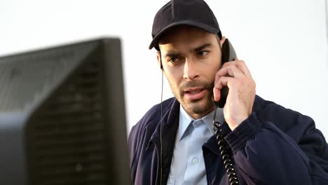 security guard talking on phone while working on computer