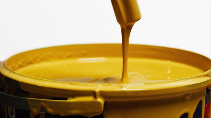 Yellow Paint Pouring and Stirring in a Bucket