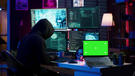 hacker che utilizza un portatile con schermo verde per distribuire malware su dispositivi non sicuri