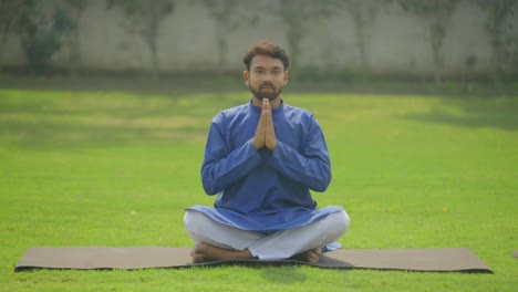 Indian-man-doing-Namaste-Yoga-in-park