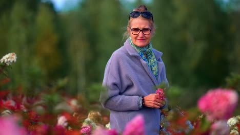 senior woman holding a flower while walking in flower fields park