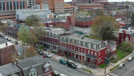 Aerial-establishing-shot-of-red-row-homes-on-urban-city-corner-intersection