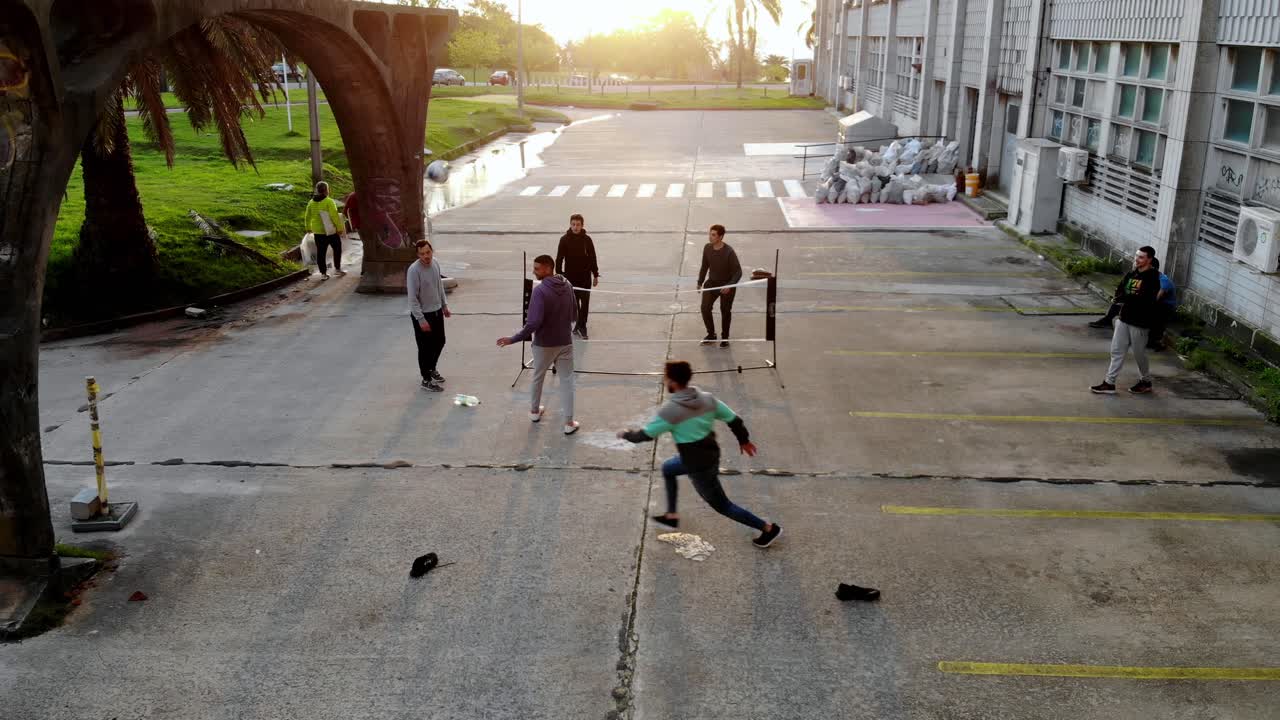 Aerial video of group of friends playing soccer tennis with a net. A sunny day at sunset in the park. Montevideo, Uruguay 4K