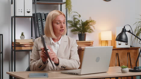 mature businesswoman using laptop talking on online communication video call at home office desk