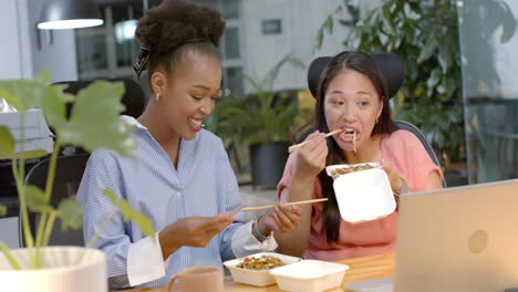 young african american woman and biracial woman enjoy a business meal at the office