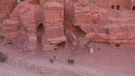 high angle view of sandstone tombs and people riding donkeys in the ancient nabatean ruins of petra jordan