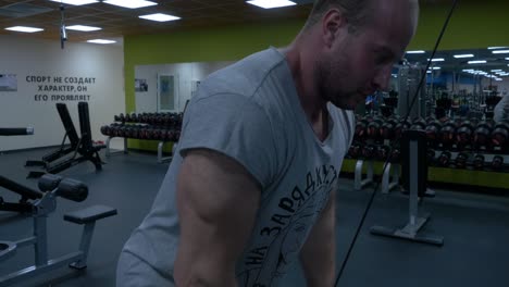 man working out biceps on cable machine in gym