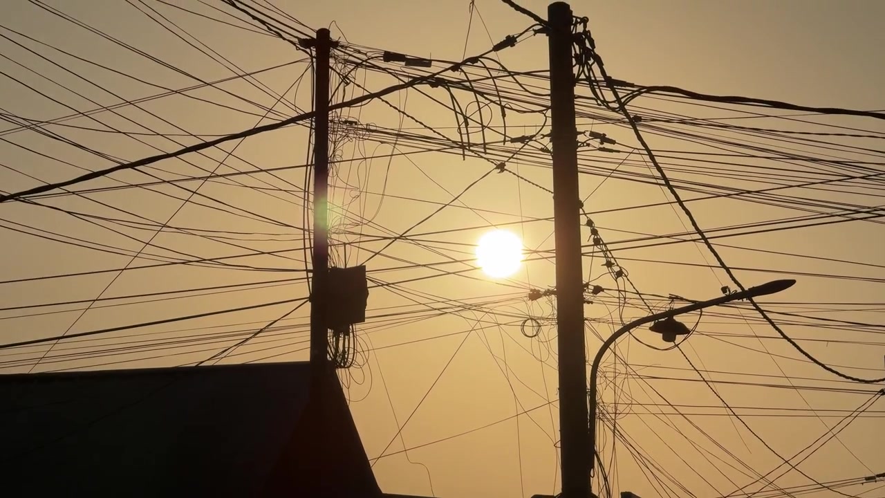 Sunset Silhouette of Tangled Power Lines and Utility Poles