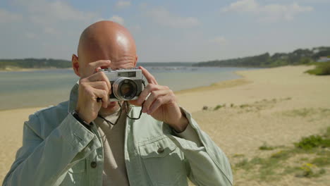 man holding camera and photographing on beach