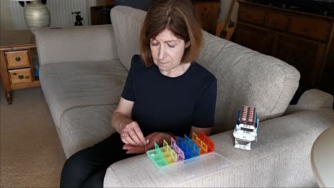 Woman-on-couch-fill-her-seven-day-medication-into-a-colored-pill-box