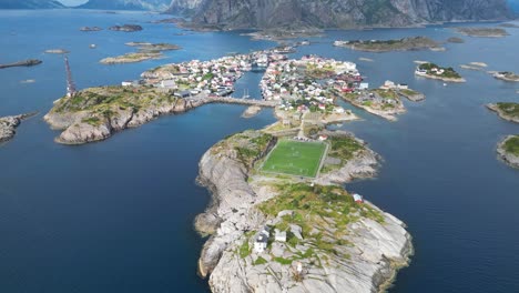 henningsvaer soccer field and village in lofoten island archipelago, norway - 4k aerial tilting up backwards