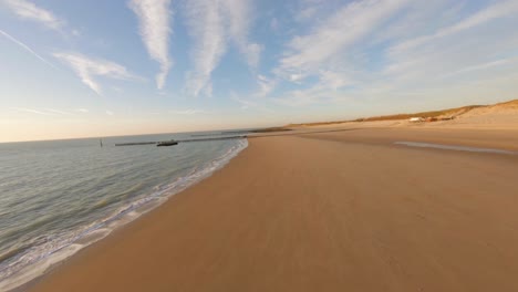 Drone-Volando-Sobre-Una-Hermosa-Playa-Vacía-Durante-Una-Puesta-De-Sol-En-Los-Países-Bajos