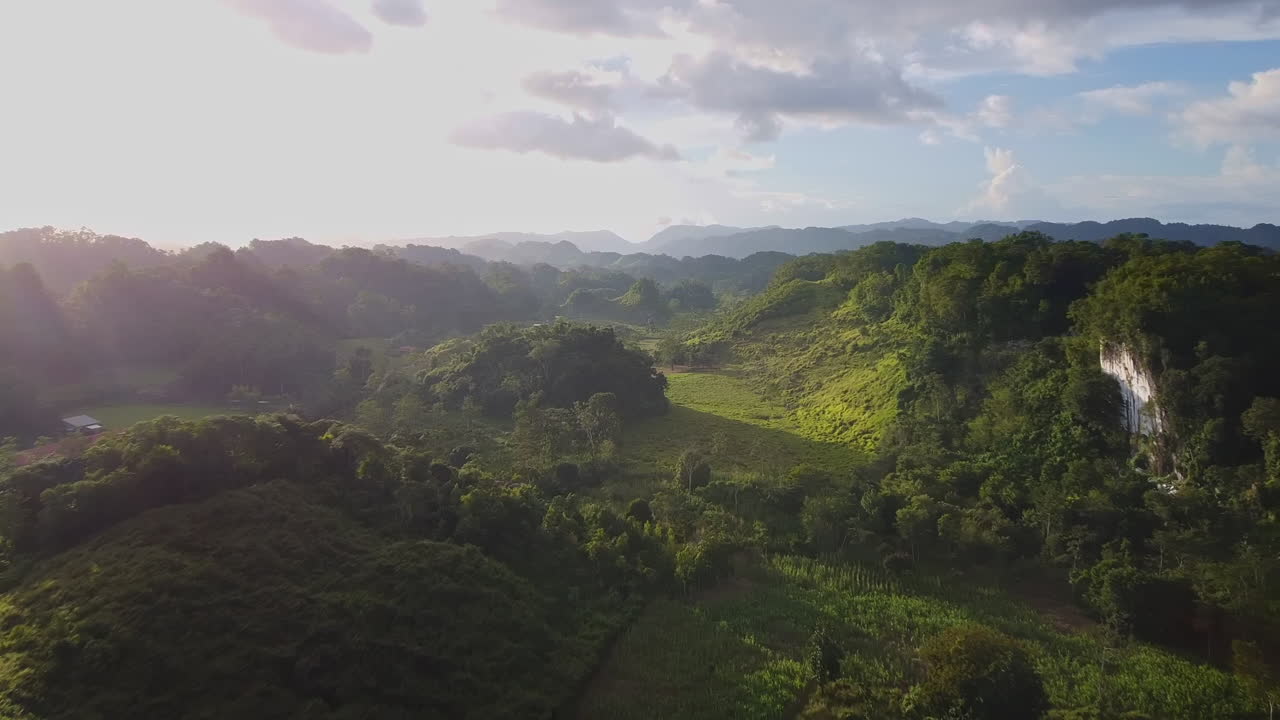 Drone flyover of sunset behind Tree covered valley