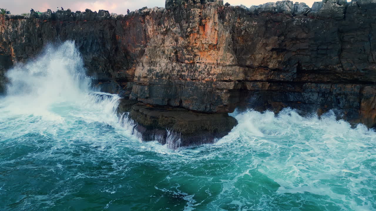 Stone cliffs washing stormy sea on overcast day. Aerial powerful ocean waves.