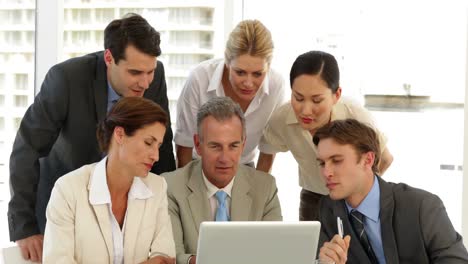 equipo de negocios positivo discutiendo algo en la computadora portátil
