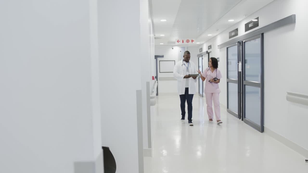 Médicos diversos ocupados usando tablet e conversando no hospital em câmera lenta