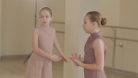 un grupo de jóvenes estudiantes de ballet con ropa de baile negra practicando posiciones en un amplio estudio de ballet con pisos de madera y barras montadas en la pared. expresiones enfocadas y movimientos sincronizados.