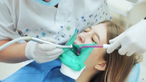 a dentist with a drill is treating a tooth to a girl patient in a dental clinic