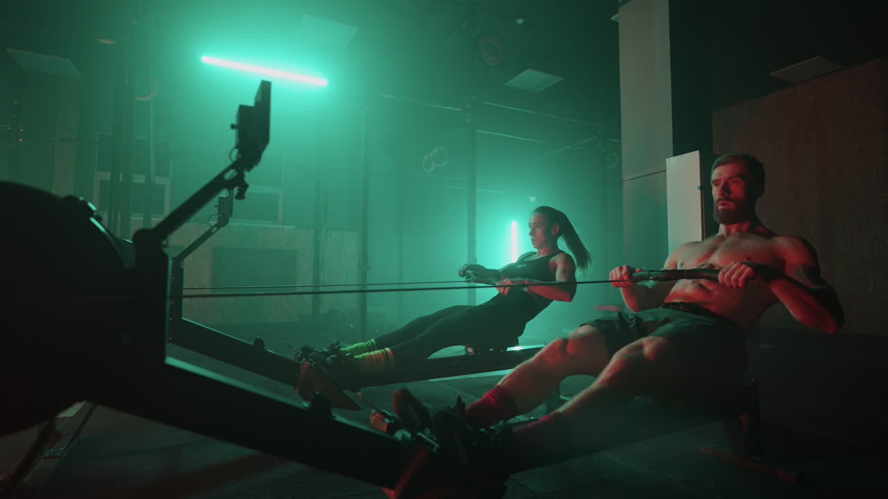 크로스피트 체육관 의 훈련 시 ⁇ 레이터 에서 근육적 인 남자 와 운동적 인 여자 의 운동. 근육적 인 스포츠 남자 와 여성 의 운동 시 ⁇ 레이터 에서 체육관 에서 운동 하는 여자 선수 들