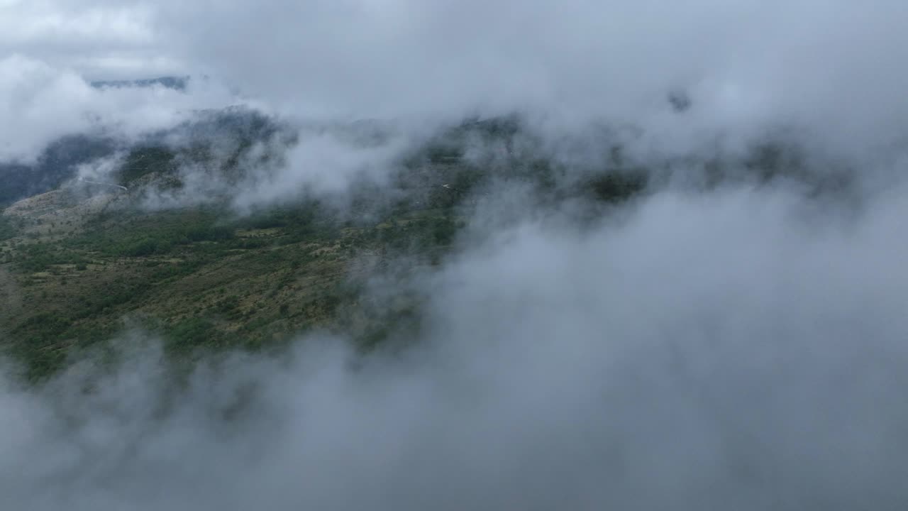 Push in drone shot of clouds in the mountain during the day in a rural zone near Cetinje, Montenegro