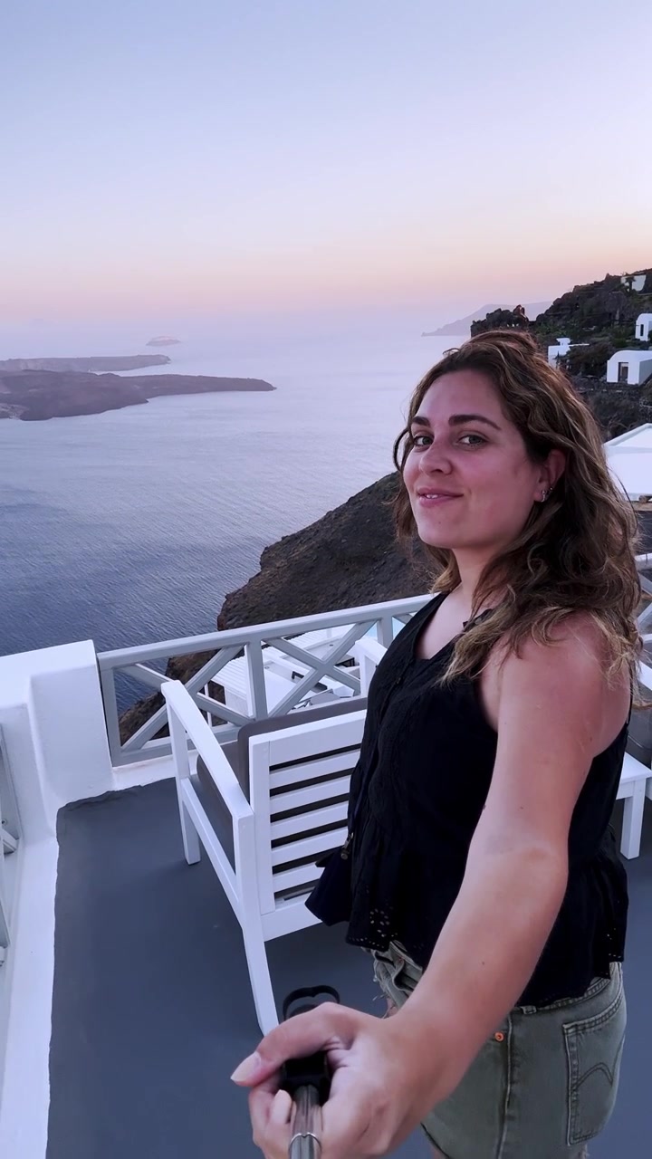 Influencer vlogging with a selfie stick in santorini, greece
