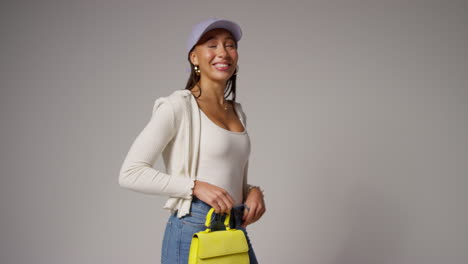 female social media influencer producing user generated content modelling yellow and orange fashion handbags in studio