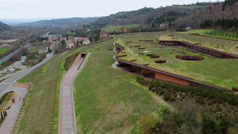 Aerial View of a Stunning Modern Winery in the Heart of Chianti Classico with people walking in the vineyards on the roof