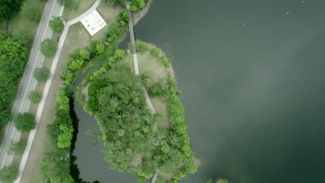 drone top-down view of a public park with a pond and some pedestrian roads