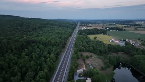 an aerial view of traffic on a highway in the late evening light with the last color of the sunset leaving the sky